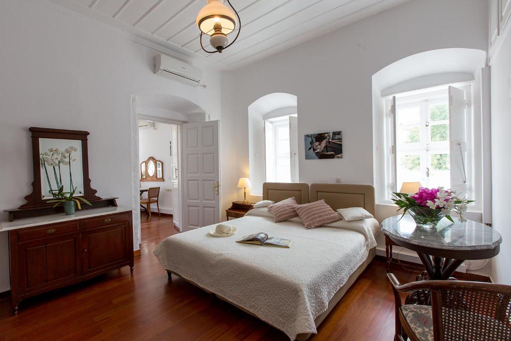 um quarto branco com uma cama e uma mesa em Hotel Miranda em Hydra