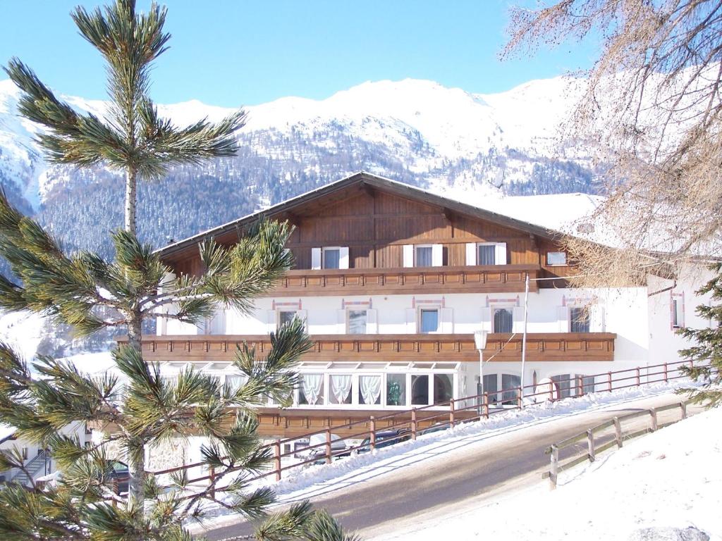 um grande edifício com árvores em frente a uma montanha em Hotel Etschquelle em Resia