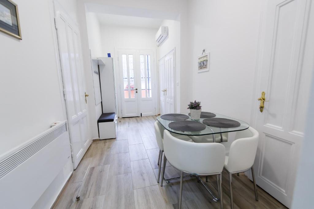 une salle à manger avec une table en verre et des chaises blanches dans l'établissement Apartman Royal, à Slavonski Brod