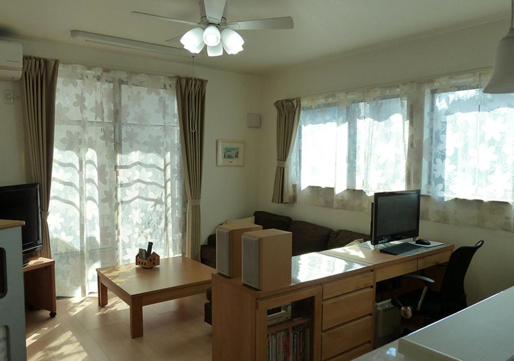 een woonkamer met een bank en een bureau met een computer bij Kanaloa Funabashi in Funabashi