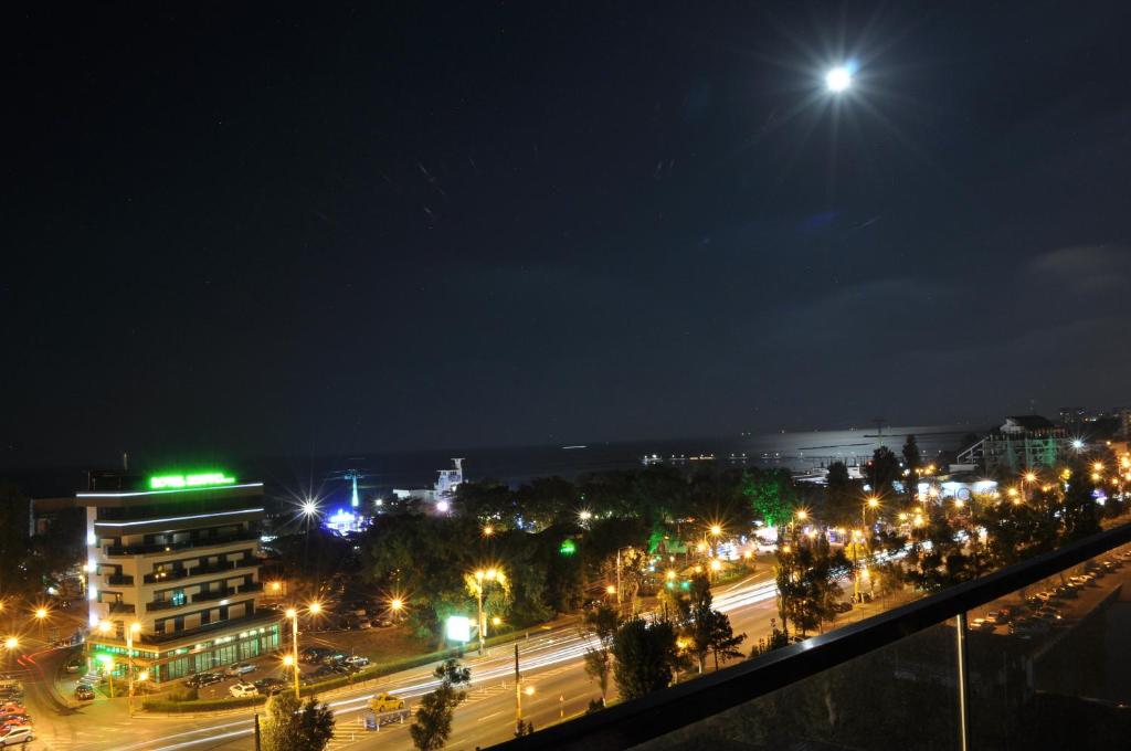 una città di notte con luci di strada e l'oceano di Hotel Scapino a Mamaia