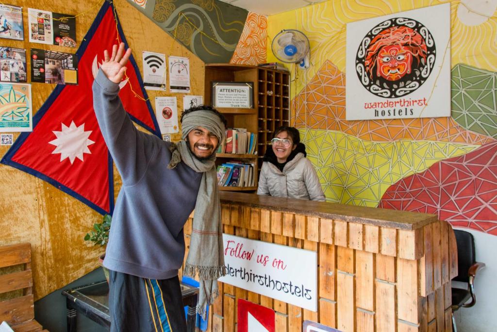 een man die voor een toonbank staat met zijn hand in de lucht bij Wander Thirst in Kathmandu