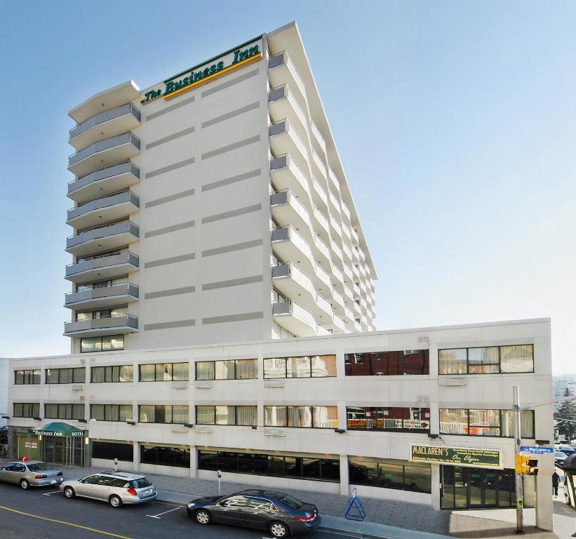 un edificio blanco alto con coches estacionados frente a él en The Business Inn, en Ottawa