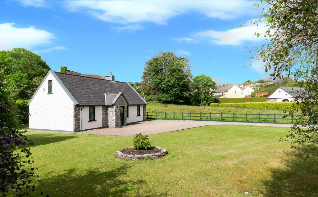 una piccola casa bianca in un prato di Fado Cottage Kenmare a Kenmare