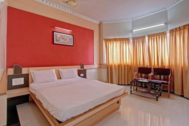 - une chambre avec un grand lit et un mur rouge dans l'établissement Bharati Lodge, à Hubli