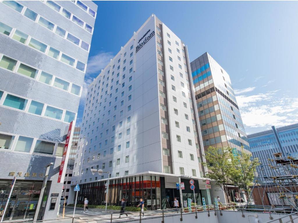 ein hohes weißes Gebäude mit zwei hohen Gebäuden in der Unterkunft JR Kyushu Hotel Blossom Hakata Central in Fukuoka