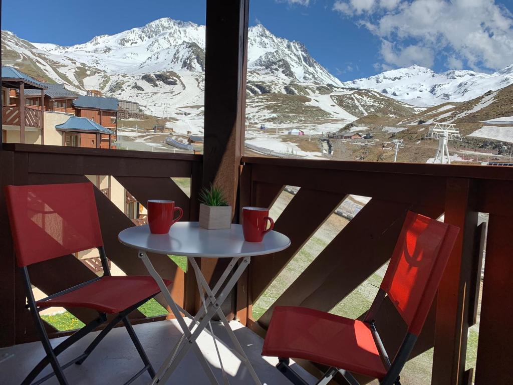 einen Tisch und zwei Stühle auf einem Balkon mit schneebedeckten Bergen in der Unterkunft Val Thorens Temple of the Sun - ski in, ski out in Val Thorens