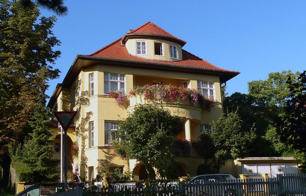 un bâtiment jaune avec un toit rouge et des fleurs sur lui dans l'établissement Pension Villa Gisela, à Weimar