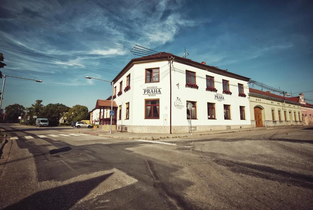 un edificio bianco all'angolo di una strada di Restaurace a Penzion Praha a Dolní Dunajovice