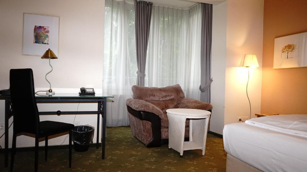 a hotel room with a desk and a chair and a bed at Entrée Groß Borstel Garni Hotel in Hamburg