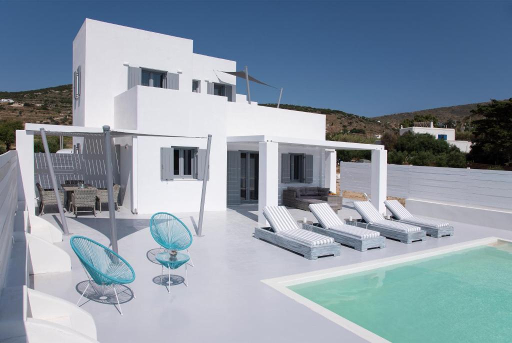 a white house with chairs and a swimming pool at PAROS ELITAS VILLAS in Parikia