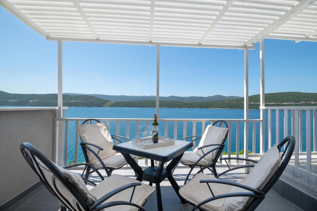 een balkon met stoelen en een tafel met uitzicht op het water bij Apartments Lukrecia in Neum