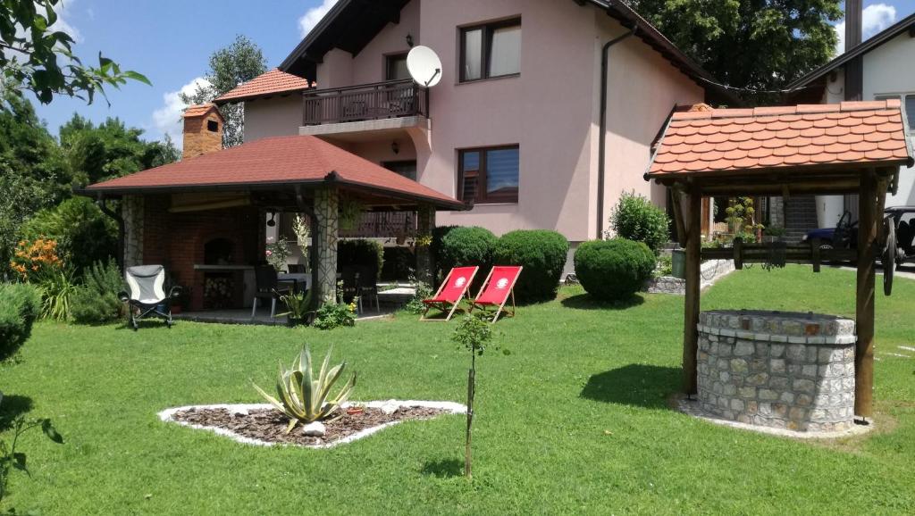 ein Haus mit zwei Gartenstühlen und einem Pavillon in der Unterkunft Apartments Dedic in Dubrave Gornje