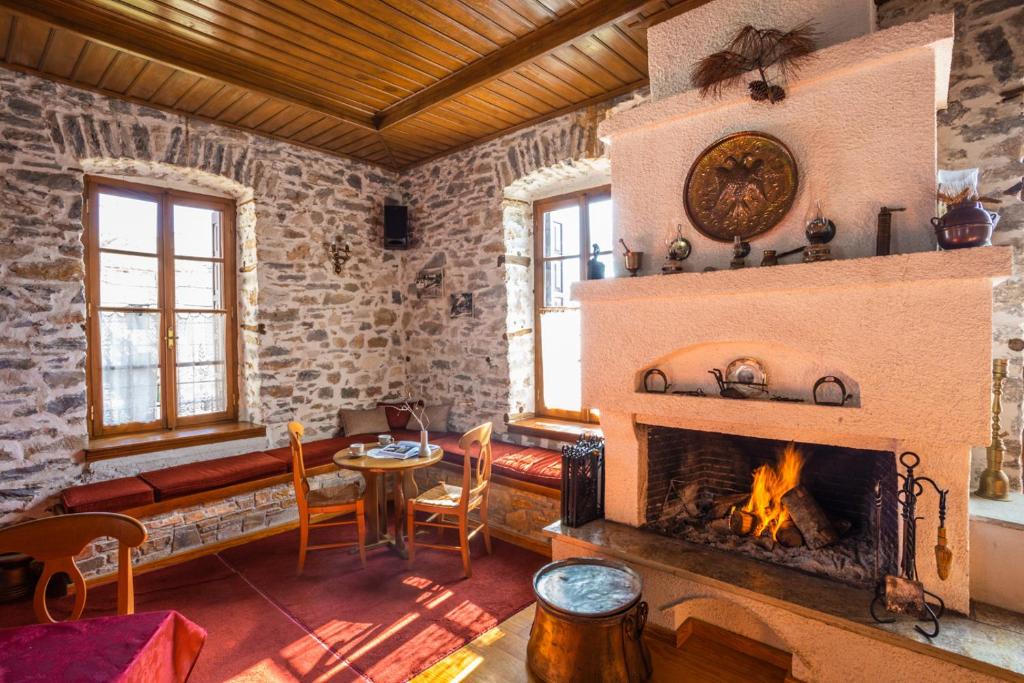 uma sala de estar com lareira e uma mesa e cadeiras em Archontiko Montana em Vizitsa