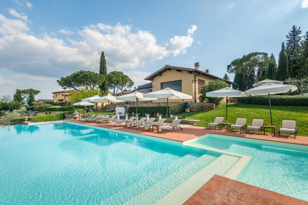 een zwembad met stoelen en parasols bij Borgo Divino in Montespertoli