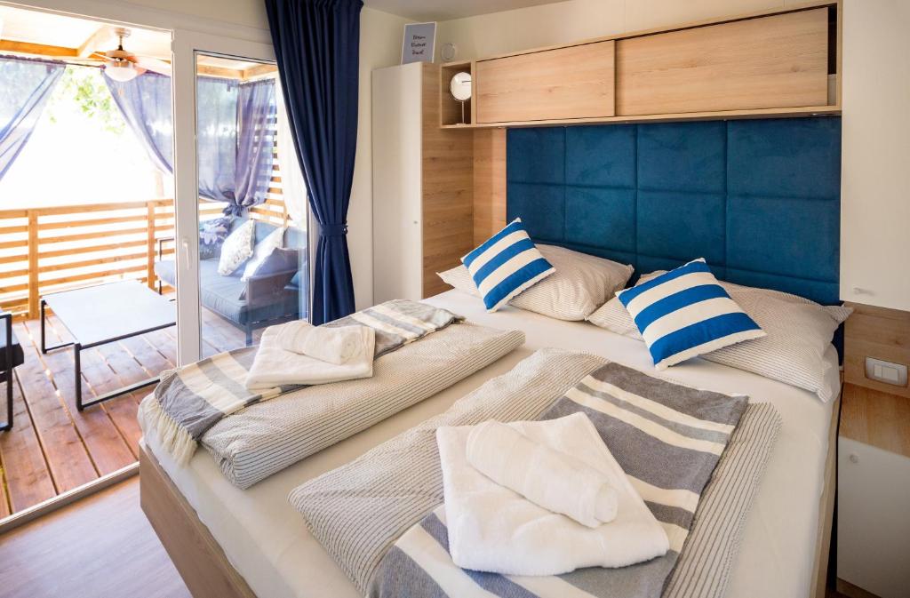 een slaapkamer met een groot bed met een blauw hoofdeinde en kussens bij Mobile Home HappyNest in Biograd na Moru