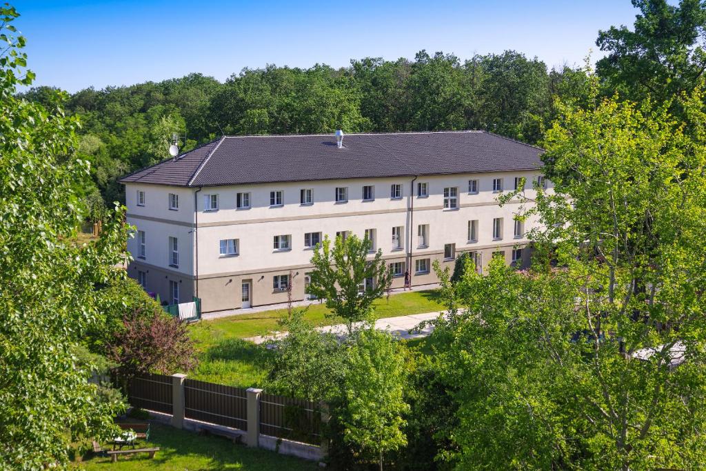 een groot wit gebouw met een zwart dak bij Penzion Lesni in Milovice