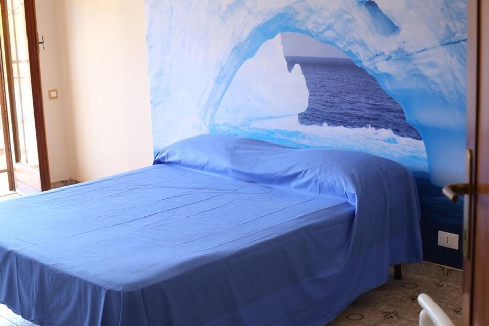 ein Schlafzimmer mit einem blauen Bett und einem Gemälde des Ozeans in der Unterkunft LA CASA DELL'ORSO in Ciampino