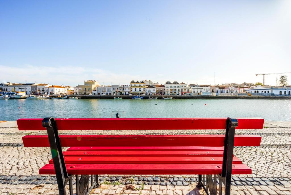 einer roten Bank, die neben einem Wasserkörper sitzt in der Unterkunft Residencial Mares in Tavira