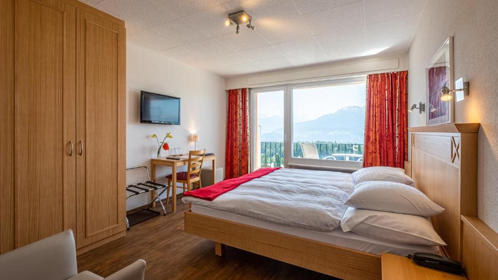 een slaapkamer met een bed en een groot raam bij Hôtel Splendide in Crans-Montana