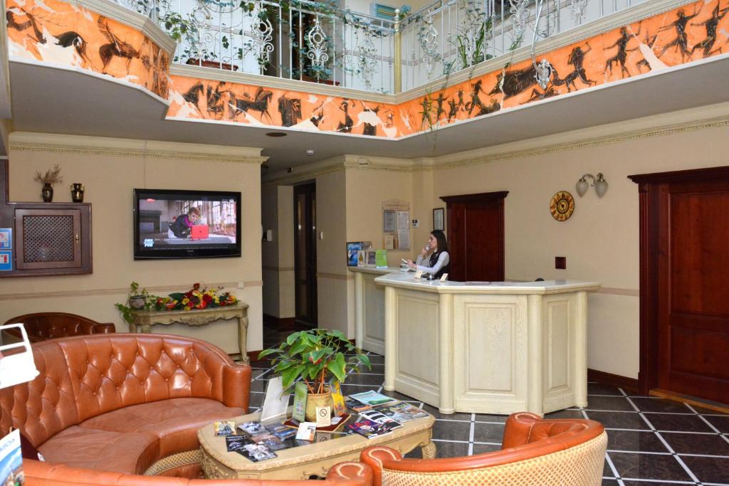 Eine Lobby mit einer Frau, die an einem Tresen sitzt. in der Unterkunft Atrium Hotel in Iwano-Frankiwsk