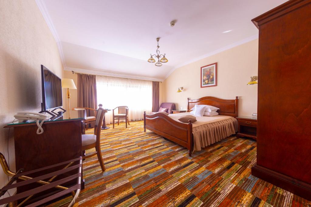 a hotel room with a bed and a table and chairs at Vila Preciosa in Alba Iulia