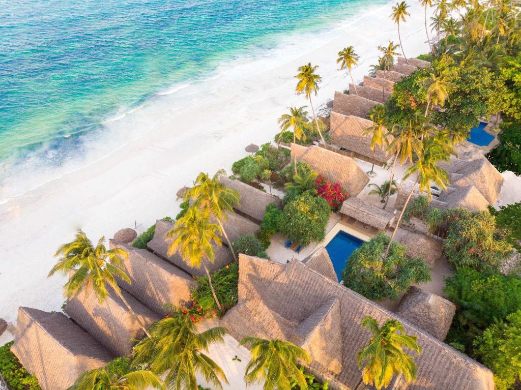 eine Luftblick auf einen Strand mit Palmen und Hütten in der Unterkunft Zanzibar Sunrise at Bandas in Matemwe