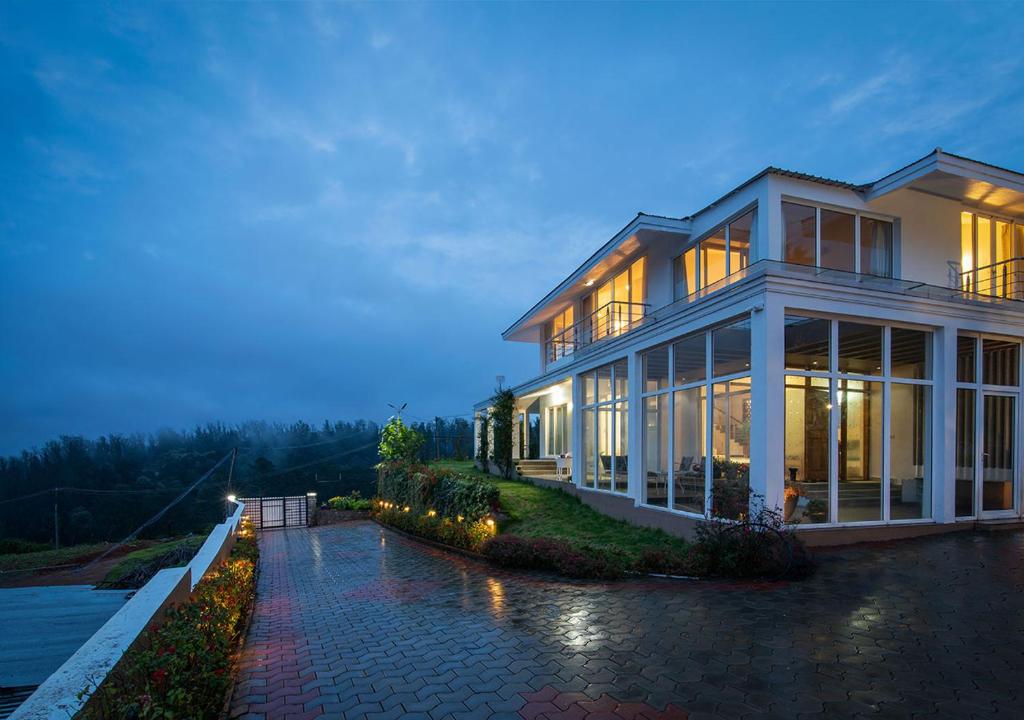 ein großes Haus mit vielen Fenstern in der Unterkunft StayVista at The Lilly Ooty with Breakfast in Udagamandalam