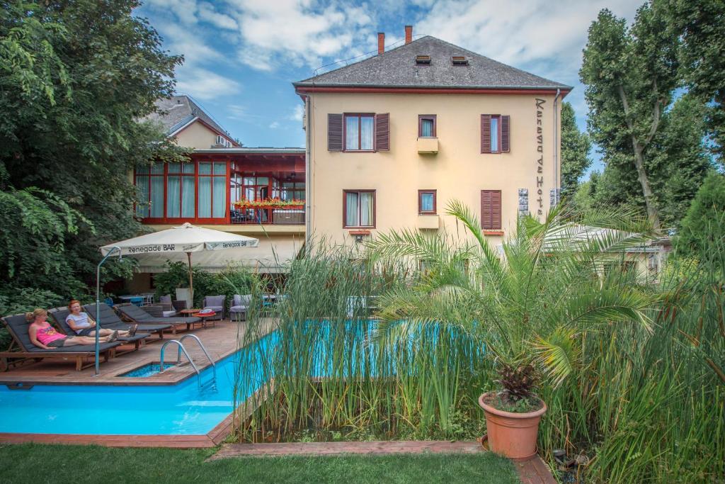 ein Haus mit einem Pool vor einem Haus in der Unterkunft Renegade Hotel in Siófok