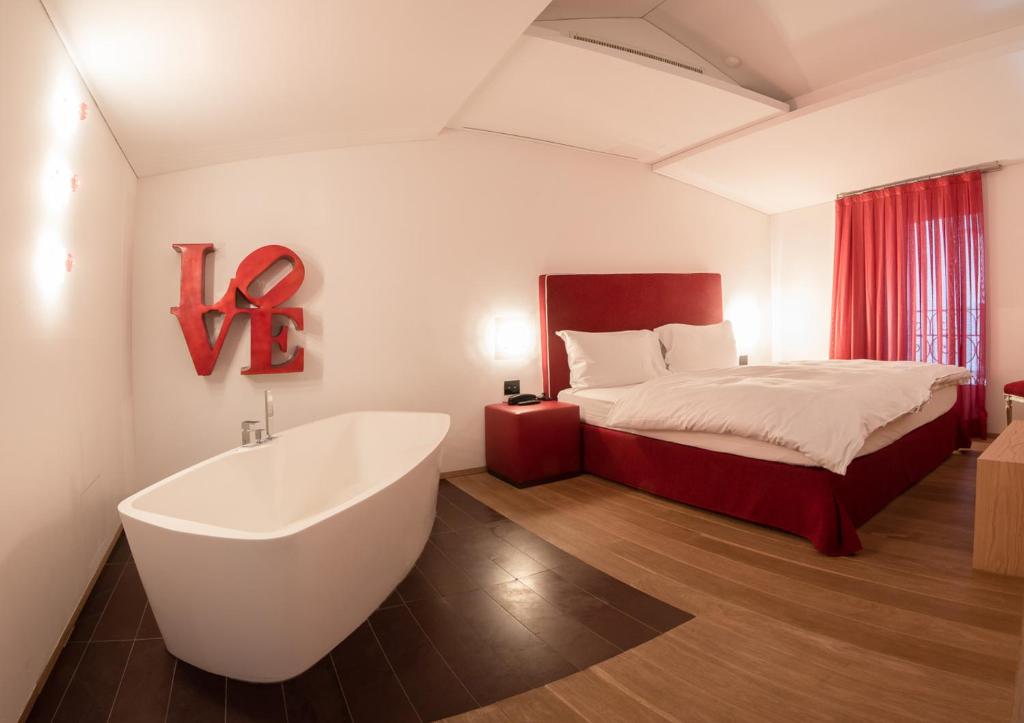 uma casa de banho com uma banheira e uma cama e uma cama e uma cama em Hotel Gabbani em Lugano