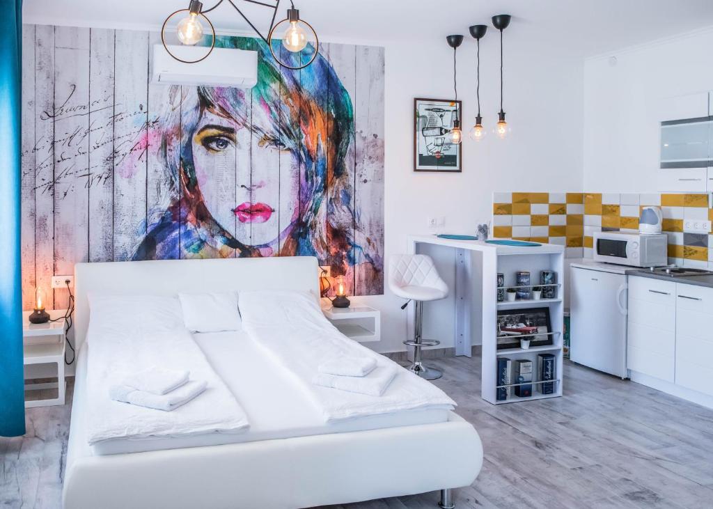 een slaapkamer met een wit bed en een schilderij aan de muur bij Jázmin Apartman in Makó