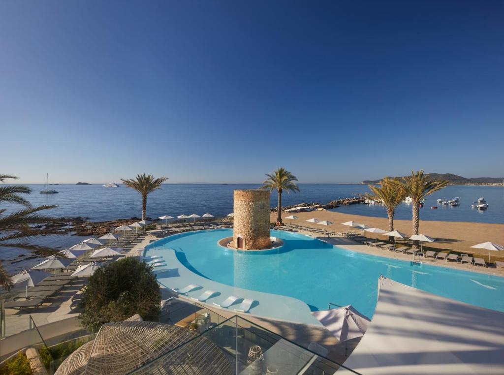 einen Pool mit Sonnenschirmen und einen Strand in der Unterkunft Hotel Torre del Mar - Ibiza in Playa d'en Bossa