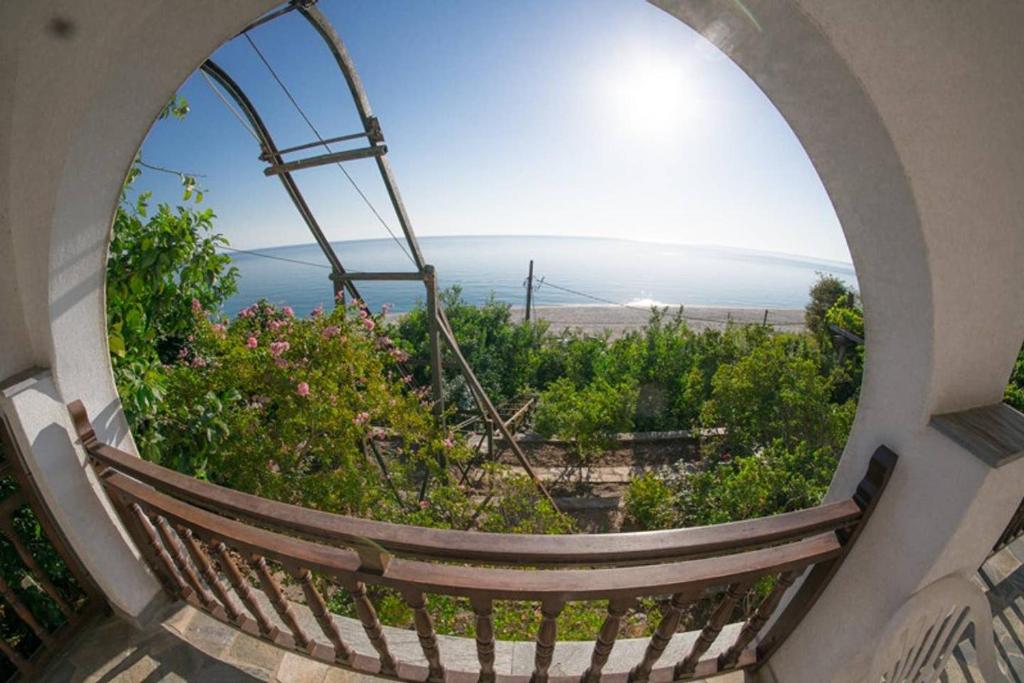 een rond raam met uitzicht op de oceaan bij Beach house Chorefto in Chorefto