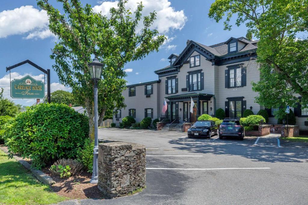 un grande edificio bianco con auto parcheggiate in un parcheggio di The Carriage House Inn Newport a Middletown