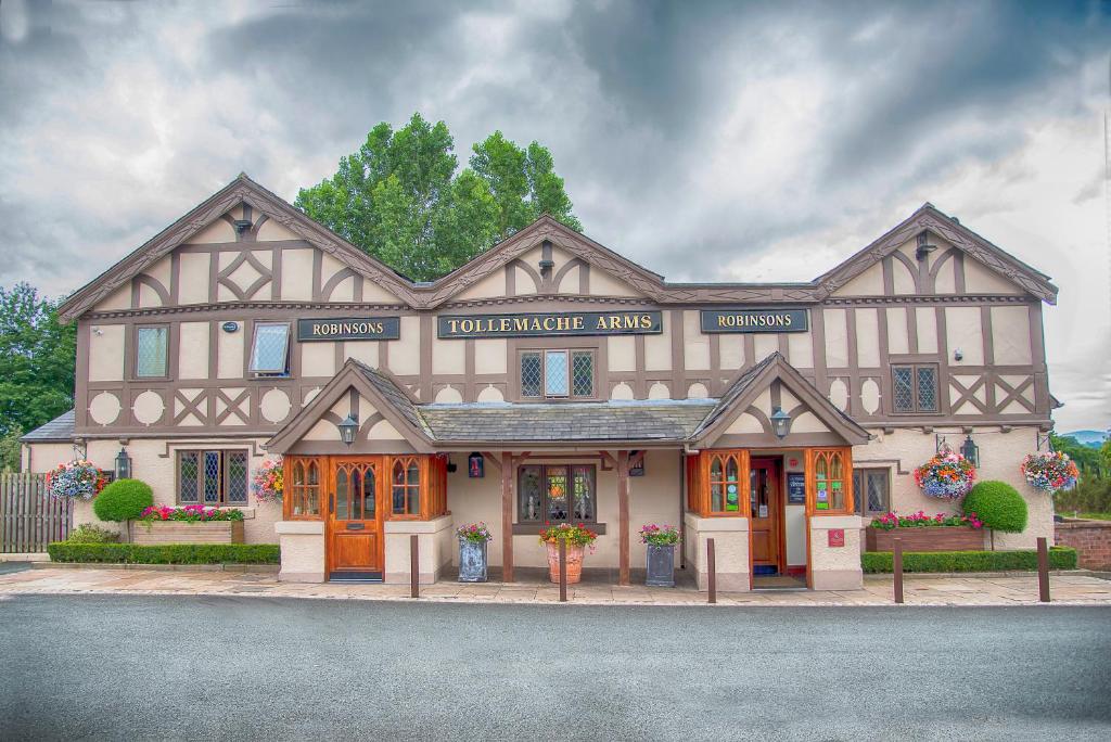 un grand bâtiment avec un magasin devant lui dans l'établissement Tollemache Arms, à Calveley