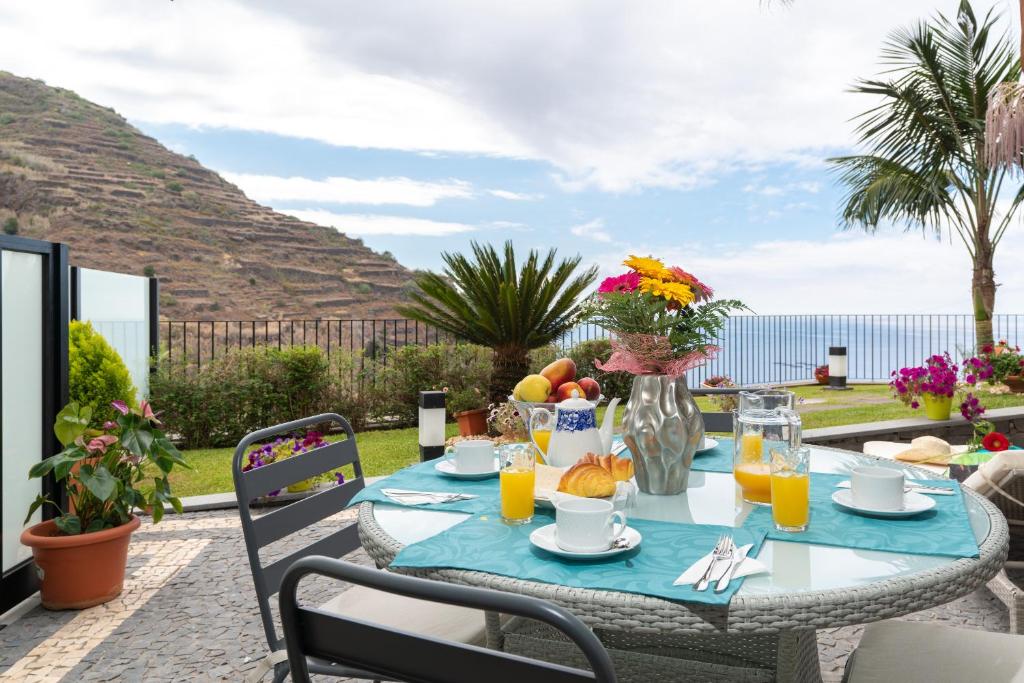 - une table avec des fruits et des jus de fruits sur une terrasse dans l'établissement Zeza´s Garden, à Calheta