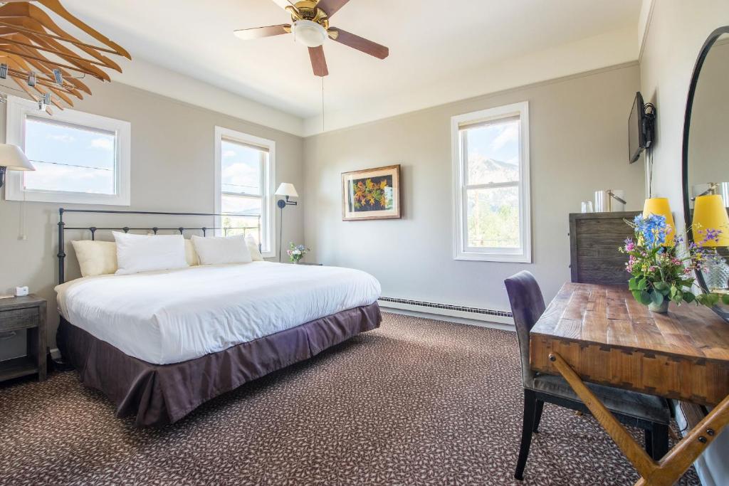 a bedroom with a bed and a desk and windows at Elk Mountain Lodge in Crested Butte