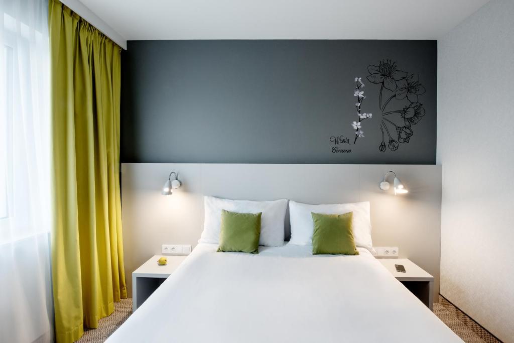 ein Schlafzimmer mit einem großen weißen Bett mit grünen Kissen in der Unterkunft ibis Styles Siedlce in Siedlce