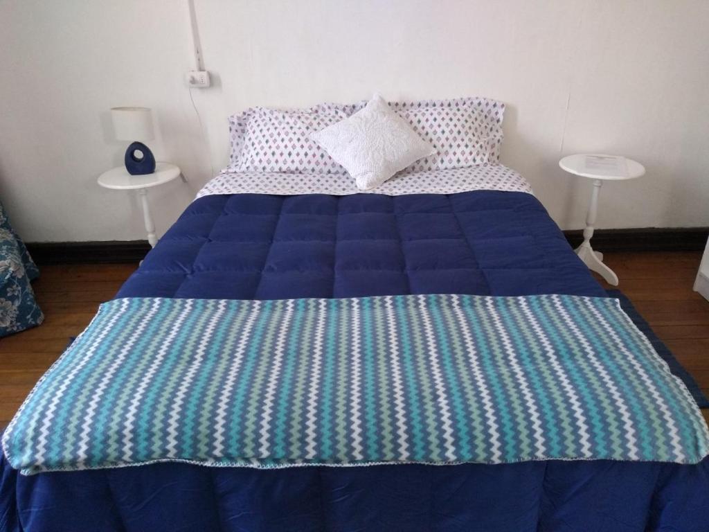 - un lit bleu dans une chambre avec deux tables dans l'établissement Casa Capilla, à Valparaíso