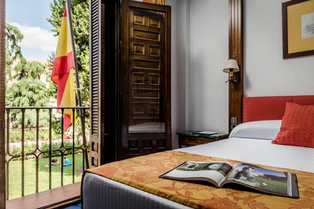 a bedroom with a bed and a balcony with a book on it at Hotel El Bedel in Alcalá de Henares