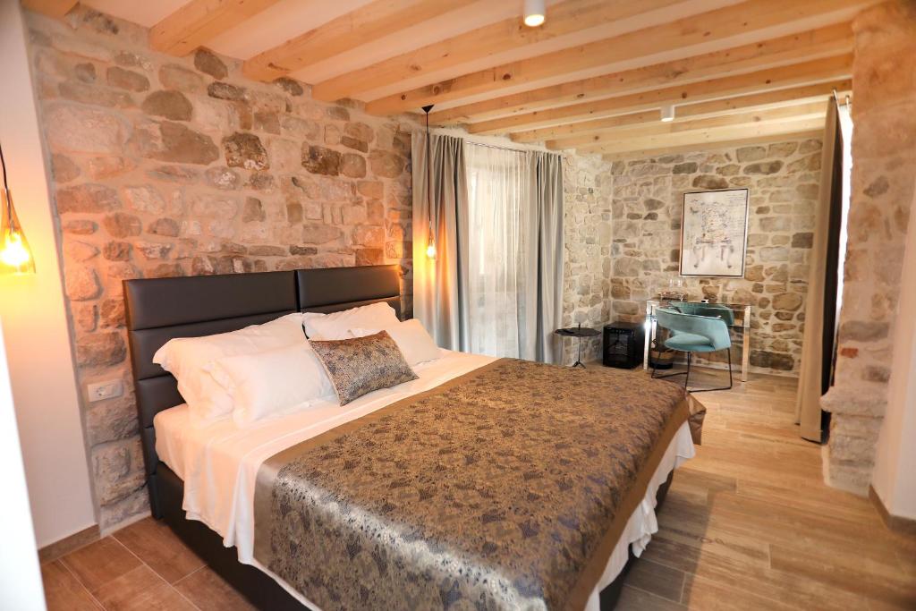 a bedroom with a large bed and a stone wall at Villa Teuta in Trogir