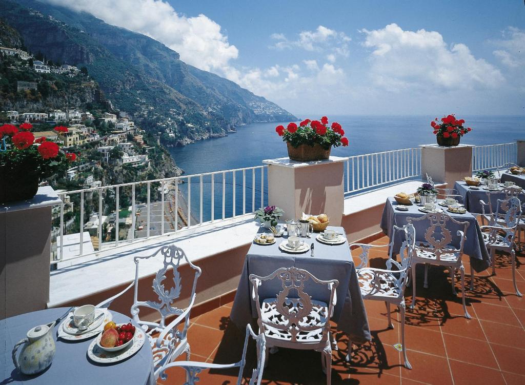 uma varanda com mesas e cadeiras e vista para o oceano em Hotel Casa Albertina em Positano