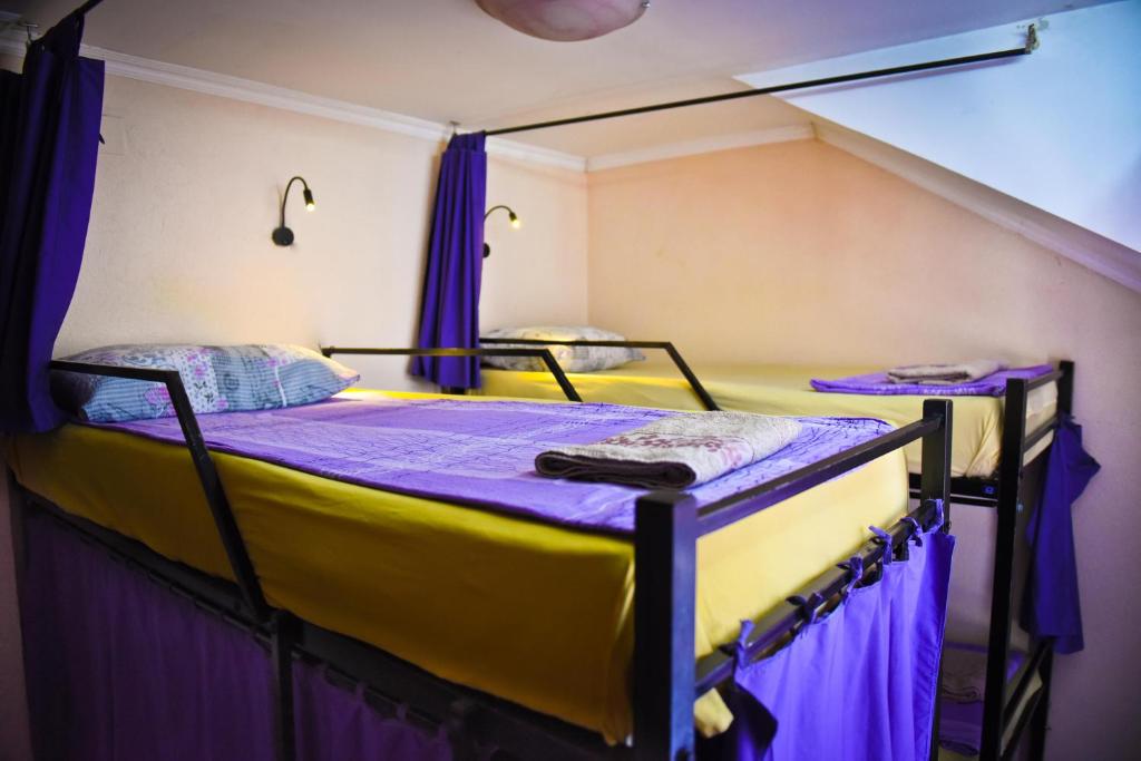 2 stapelbedden in een kamer met paarse gordijnen bij Goldy Hostel in Bitola