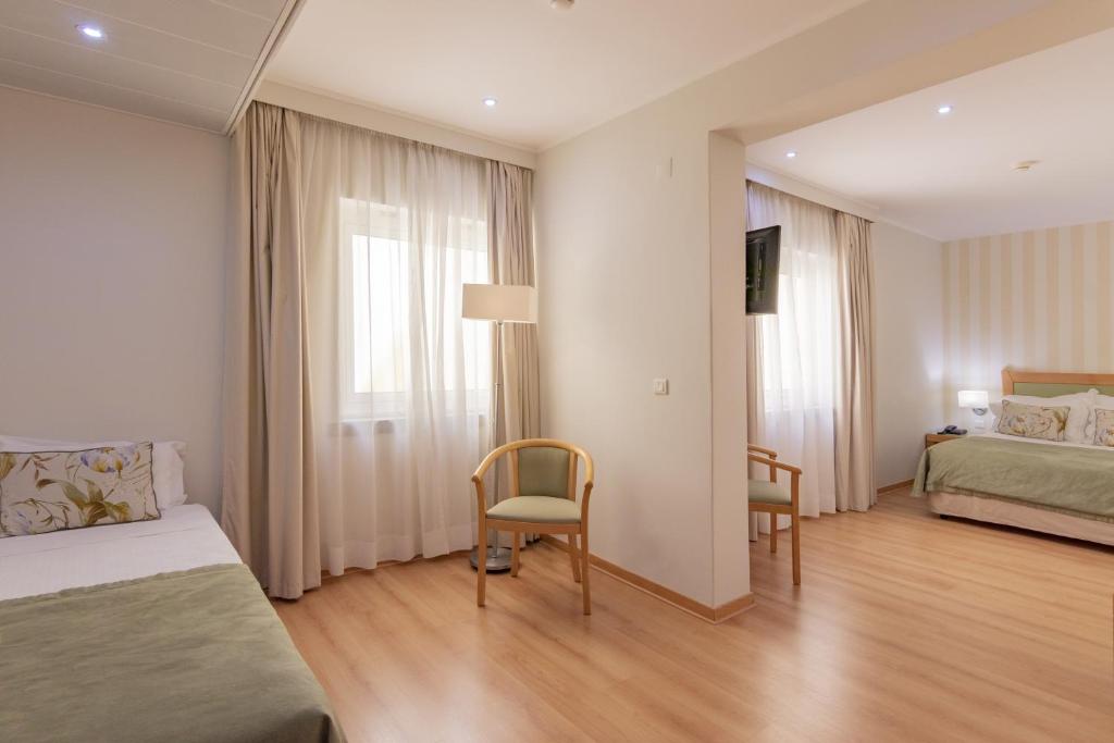 a hotel room with a bed and a table and chairs at Luna Esperanca Centro Hotel in Setúbal