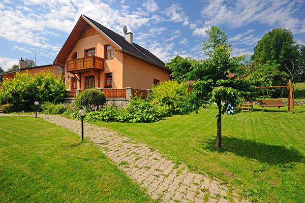 una casa con un árbol delante de una casa en Privát Majo, en Liptovský Mikuláš