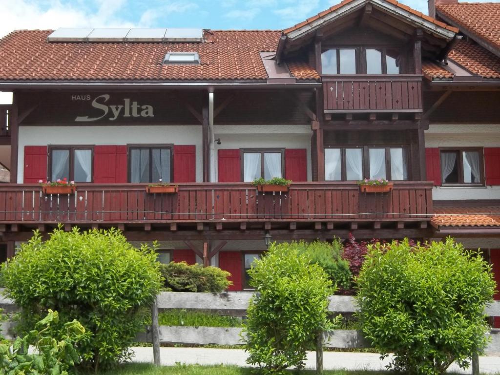 une maison avec un bâtiment rouge et blanc et des balcons dans l'établissement Haus Sylta, à Fischen im Allgäu