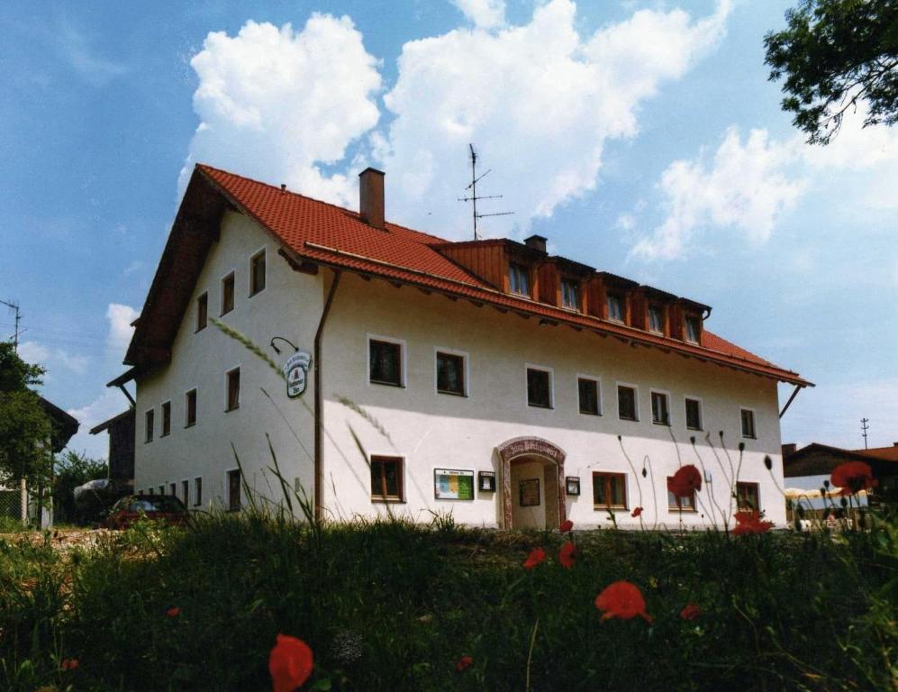 uma grande casa branca com um telhado vermelho em Gasthof zum Kirchenwirt em Kirchdorf am Inn