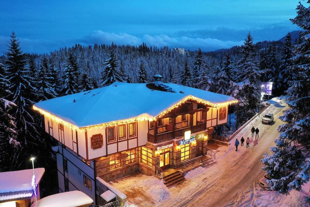 een huis in de sneeuw met lichten aan bij MPM Family Hotel Merryan in Pamporovo