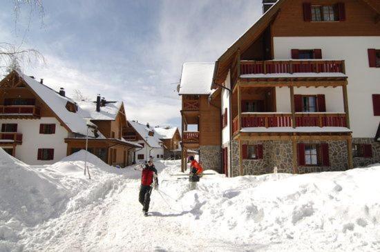 zwei Personen stehen im Schnee vor einer Lodge in der Unterkunft Antela, 142 m2 appartment for 12 person in Mariborsko Pohorje in Hočko Pohorje