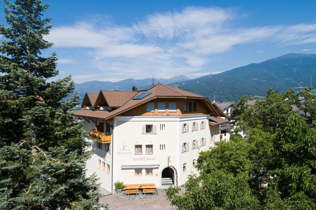 a large white building with a brown roof at Gasthof Teiser Stern in Funes